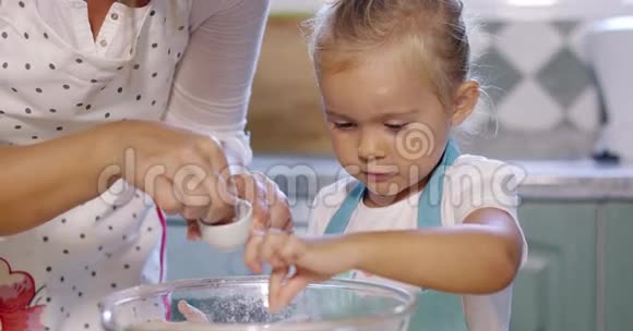 可爱的小女孩在烘焙混合物中加入盐视频的预览图