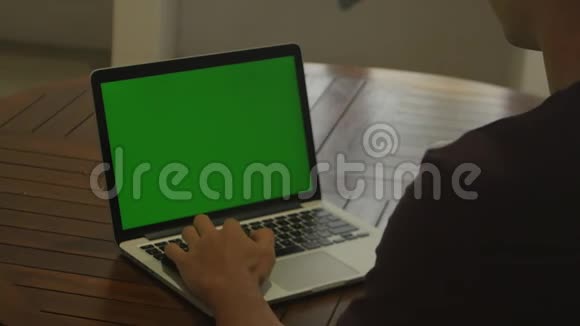 男人在家里用笔记本电脑和绿色屏幕自由职业者在家工作视频的预览图