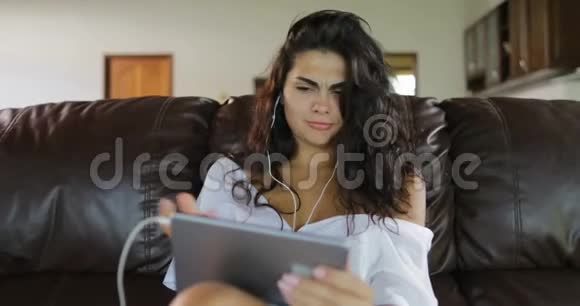 女用平板电脑坐在客厅的教练上打网络视频电话微笑女孩讲网络视频的预览图