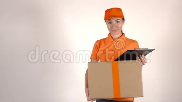 穿橙色制服的女孩快递员送了一个大纸箱浅灰色背景4K摄影棚拍摄视频的预览图