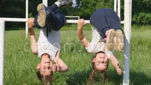 家庭运动小男孩和小女孩在足球场上做运动在单杠上做运动视频的预览图