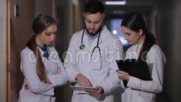 医生在医院走廊实习生解释说病人接受医生和两个女实习生分析诊断视频的预览图