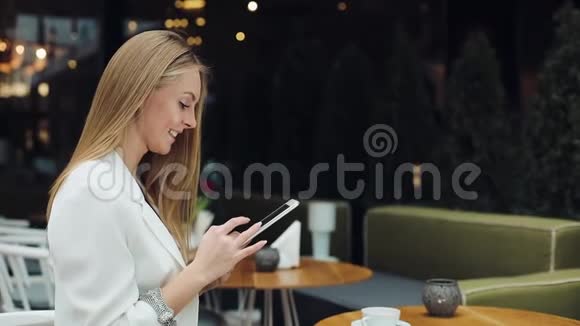 女人在咖啡馆的桌子旁坐着一块平板电脑视频的预览图