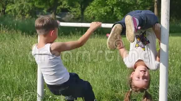 家庭运动小男孩和小女孩在足球场上做运动在单杠上做运动视频的预览图