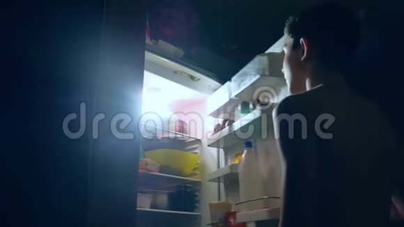 少年饮食暴食从冰箱晚上吃男孩打开冰箱和室内冰箱视频的预览图