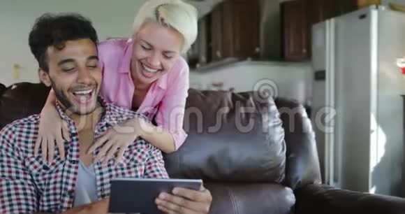 女人拥抱男人坐在教练用平板电脑在客厅交谈年轻夫妇在早晨现代视频的预览图
