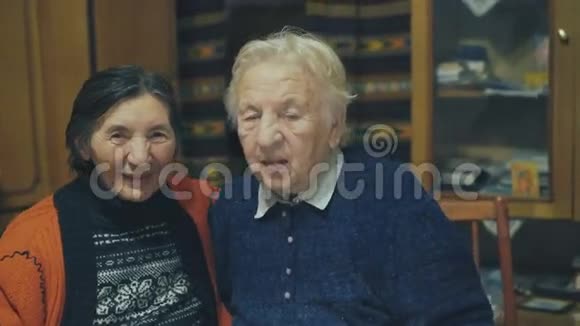 两个微笑的非常老的女人坐在节日餐桌上的肖像4K视频的预览图