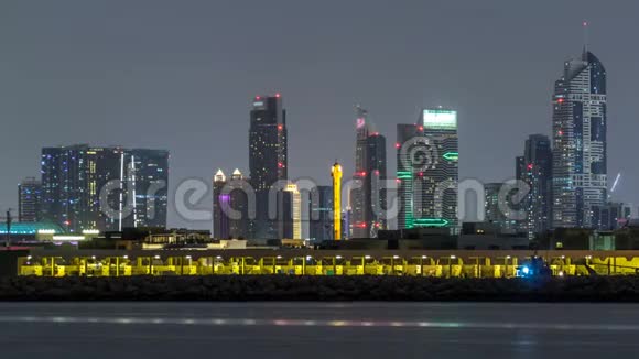 现代迪拜城市的天际线在夜晚随着明亮的摩天大楼在水面上消失视频的预览图