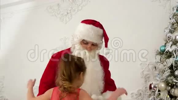 圣诞老人帮助小女孩在圣诞树上挂视频的预览图