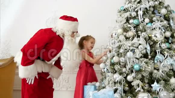 圣诞老人帮助漂亮的小女孩装饰圣诞树视频的预览图