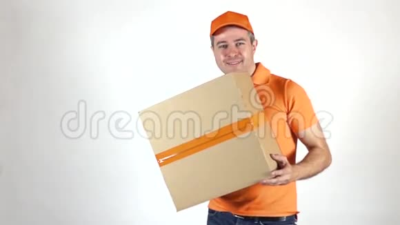 送货员穿着橙色制服朝镜头扔了一个大包裹浅灰色背景慢镜头拍摄视频的预览图