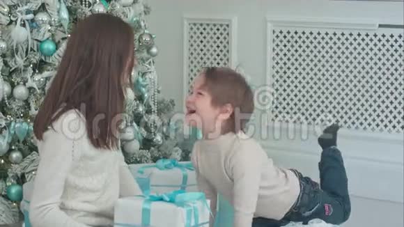 快乐的年轻妈妈和可爱的小儿子一起玩圣诞礼物视频的预览图