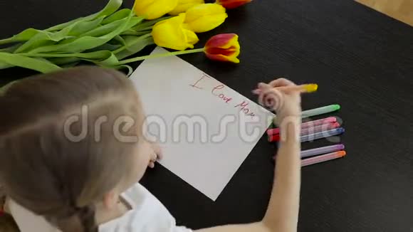 快乐的小女孩在桌子上为他妈妈做了一张节日卡片视频的预览图