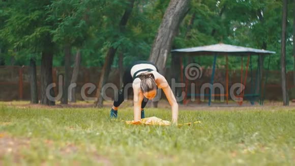 体育运动中的年轻运动员女性从事瑜伽练习躺在草地上公园的地毯上视频的预览图