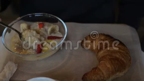 男人在咖啡馆里吃水果和牛角面包粥早餐午餐视频的预览图