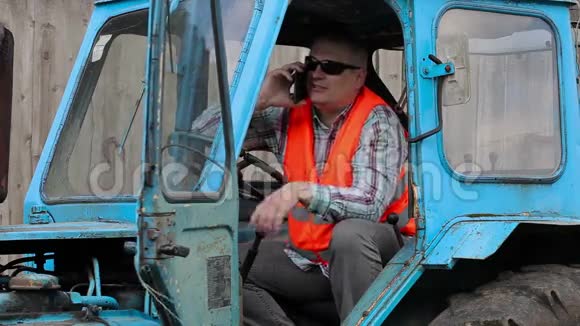 坐在拖拉机上用智能手机说话的工人视频的预览图