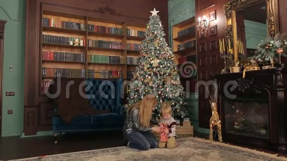 母亲和孩子在圣诞树附近打开礼物视频的预览图