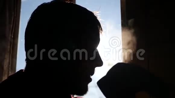 男人吹着热茶坐在窗边的背景上阳光明媚动作缓慢高清1920x1080视频的预览图