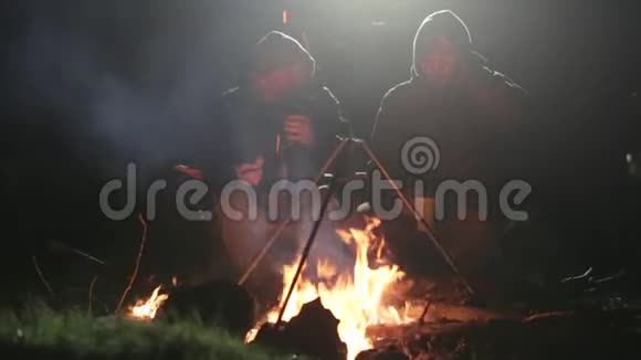 两个朋友晚上坐在柴火旁边聊天喝茶视频的预览图