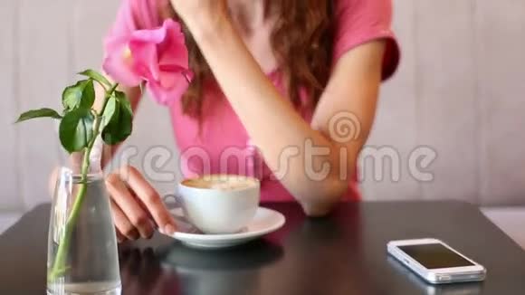 女人在看她的手机喝咖啡视频的预览图