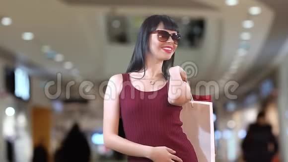 美丽的黑发女孩带着眼镜后购物中心视频的预览图