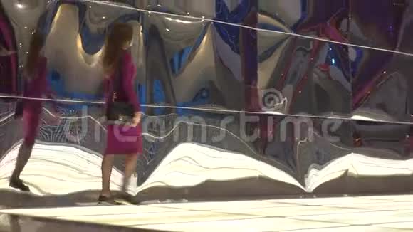 穿紫色裙子的布鲁内特女孩走着扭曲的反光墙4K视频视频的预览图