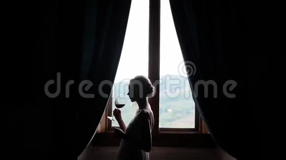 在窗户旁边喝酒的女人视频的预览图
