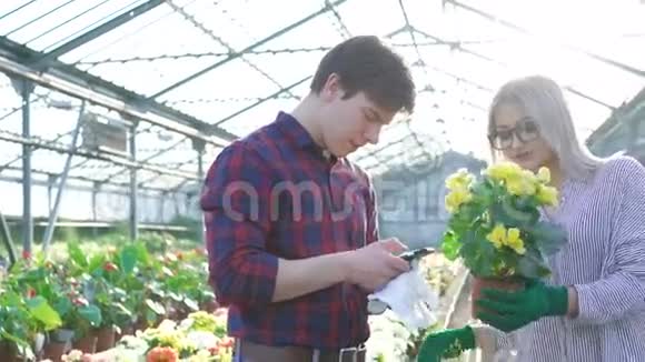 园艺师检查鲜花使用智能手机4K视频的预览图