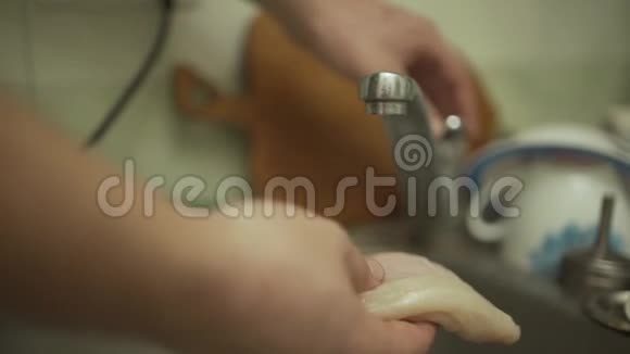 一个男人正在洗一只鸡在厨房的烤架上煮特写镜头视频的预览图