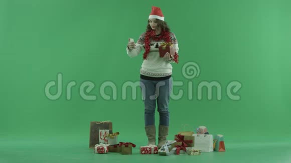 圣诞帽子上漂亮的年轻女士带圣诞礼物自拍背景色键视频的预览图