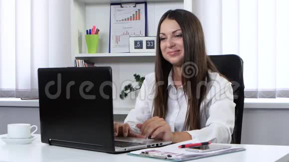 一个女孩坐在办公室手提电脑前用网络摄像机说话视频的预览图