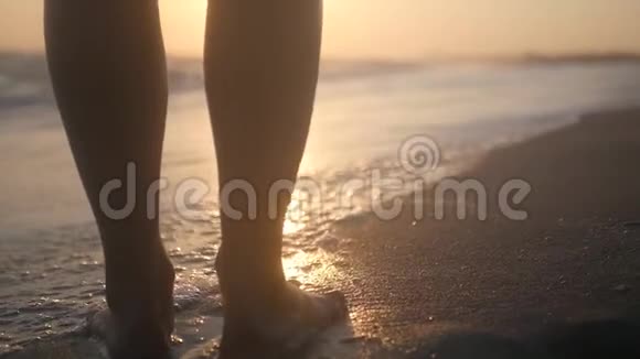 美丽的女足在美丽的日落背景下带着波浪沿着海滨散步高清1920x1080慢慢慢慢视频的预览图