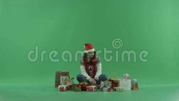 漂亮的年轻女士戴着圣诞帽得到了圣诞礼物背景上的彩色钥匙视频的预览图