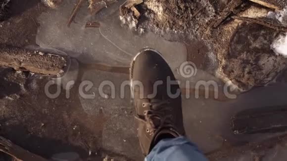 穿靴子的人的脚在肮脏的水坑上破冰视频的预览图
