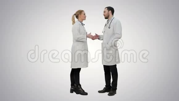 快乐的医生和年轻的护士微笑着互相感谢在白色的背景上握手视频的预览图
