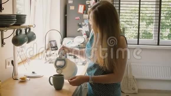 年轻快乐的妈妈在杯子里倒热水泡一杯茶慢点斯泰迪达姆视频的预览图