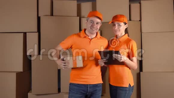 穿着橙色制服的快递员站在棕色纸箱堆后面快递公司的员工4K工作室视频视频的预览图