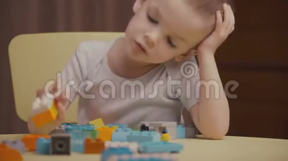 一个快乐的小男孩在家里玩一个五颜六色的建筑积木视频的预览图