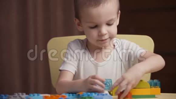 一个快乐的小男孩在家里玩一个五颜六色的建筑积木视频的预览图