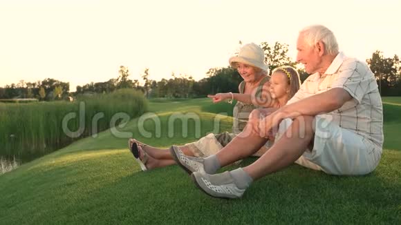 女孩和祖父母坐在草地上视频的预览图