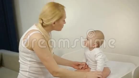 妈妈微笑着看着坐着的婴儿视频的预览图
