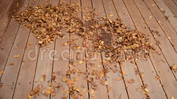 一个人在木天井上把秋叶扫成一大堆视频的预览图