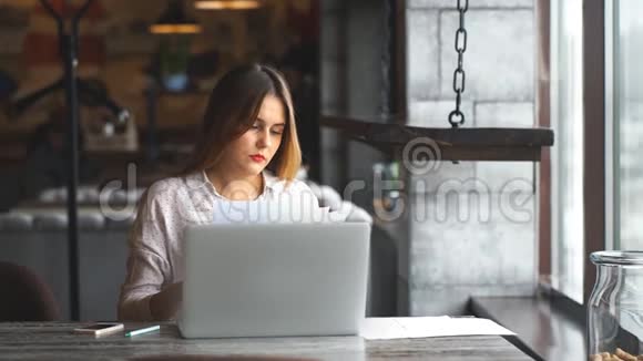 女商人用手提电脑在咖啡馆里检查文件视频的预览图