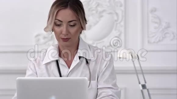 严重女医生使用她的笔记本电脑在医疗办公室视频的预览图