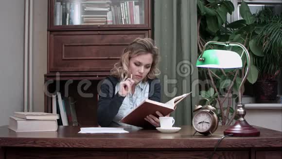 年轻女性集中精力阅读一本书手里拿着一支铅笔坐在办公桌前她的男同事带她来视频的预览图
