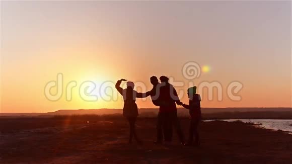 欢乐的家庭舞蹈在湖岸剪影日落视频的预览图