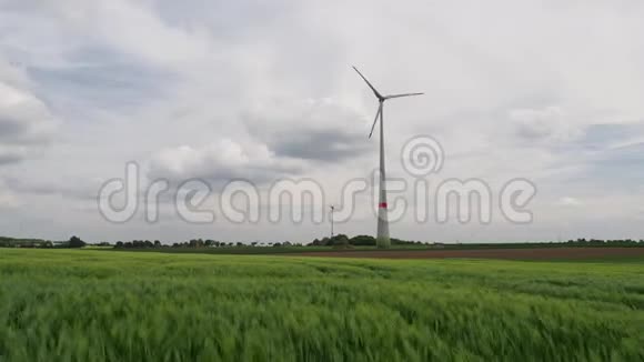 两个风车在一个麦田后面的大风中视频的预览图