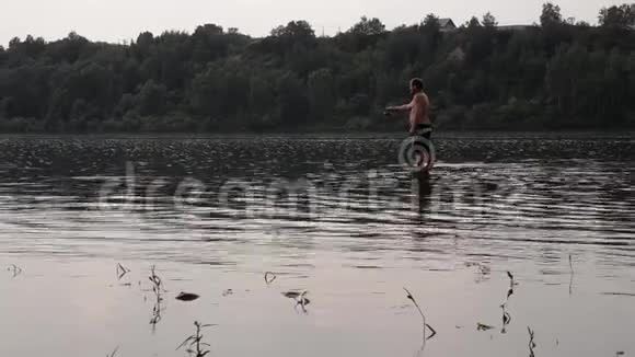 半裸的渔夫拿着鱼竿在平静的河里钓鱼视频的预览图