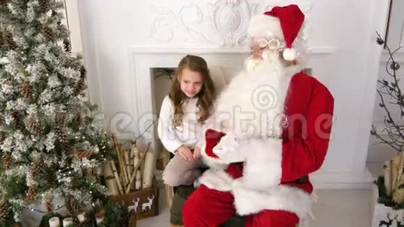 可爱的小女孩和圣诞老人一起玩视频的预览图
