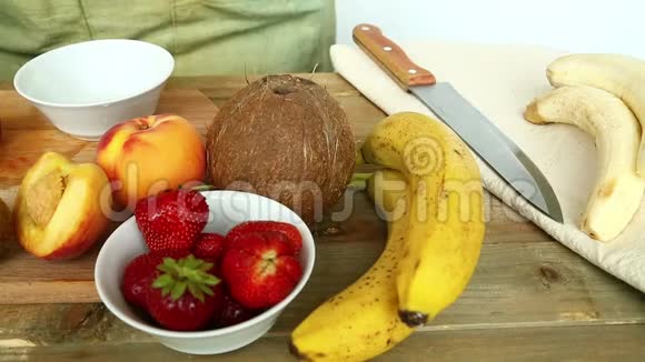 水果鸡尾酒的小板上有香蕉草莓桃子一个女人把草莓放在碗里视频的预览图